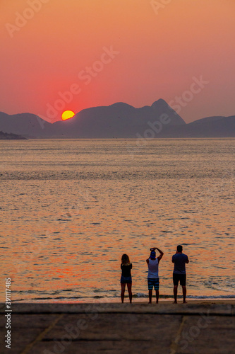 people watching the sunrise at the red beach of urca in rio de janeiro.