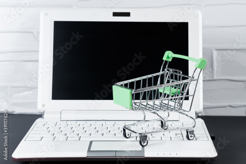 Black Friday concept. Mini shopping cart and laptop. Online sale and discount.