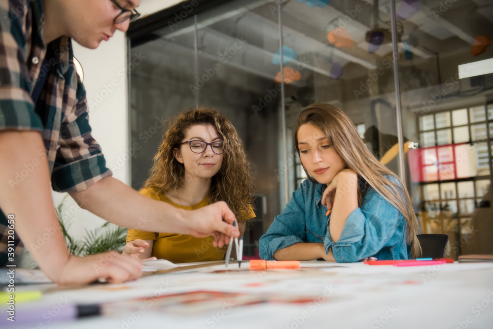 Group of designers drawing on a blueprint Group of designers drawing on a blueprint