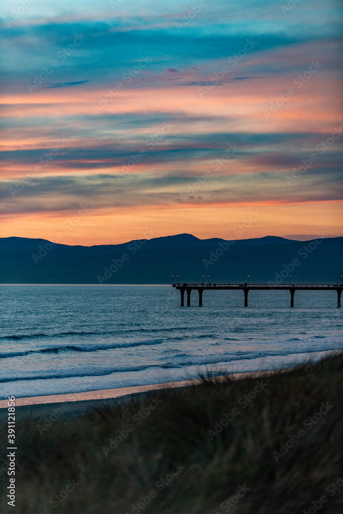 Sunset at the coast with a pier in New Zealand
