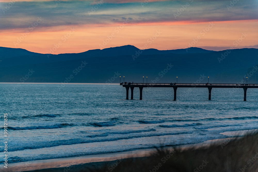 Sunset at the coast with a pier in New Zealand Sunset at the coast with a pier in New Zealand