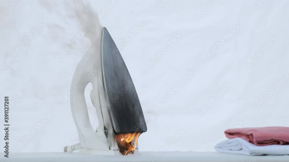 iron burns with open flame on ironing board closeup. Concept of fire occurrence from
