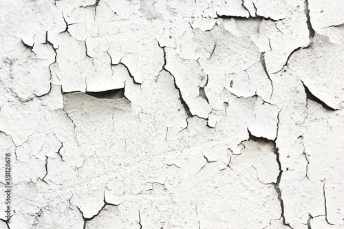 A cracked white thing on the wall.The texture is detached under the influence of the weather paint and plaster.Background with large cracks.