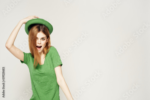 girl in green clothes with hat on light background St. Patrick's day cropped view