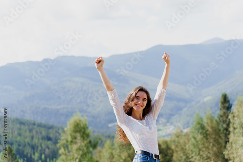 Tourism travelling in Ukraine. Girl girl raised her hands up and enjoys the mountain hills view. Feeling freedom in Karpathian mountains.
