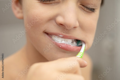 Dental education in the family  a boy with joy 10 years old  washing his teeth with toothpaste and a toothbrush in the bathroom. Healthy teeth concept. Lifestyle close-up photo