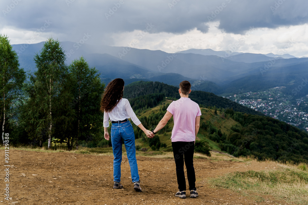 Couple looking at the mountain hills before raining. Feeling freedom together in Karpathian mountains. Tourism travelling in Ukraine.