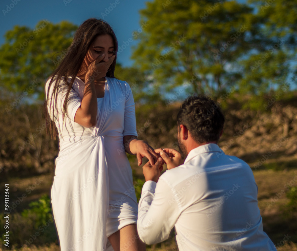 Marriage proposal of a latin couple dressed in white in a beautiful rural place with some stone walls and sunset in the background Marriage proposal of a latin couple dressed in white in a beautiful rural place with some stone walls and sunset in the background