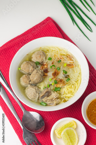 Bakso Sapi or Meatball traditional popular street food in Indonesia, served with clear soup, and noodles. Grey wooden background. Selective focus, copy space. 