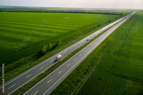 ambulance car driving on asphalt road along the green fields. seen from the air. Aerial view landscape. drone photography. Sunset time