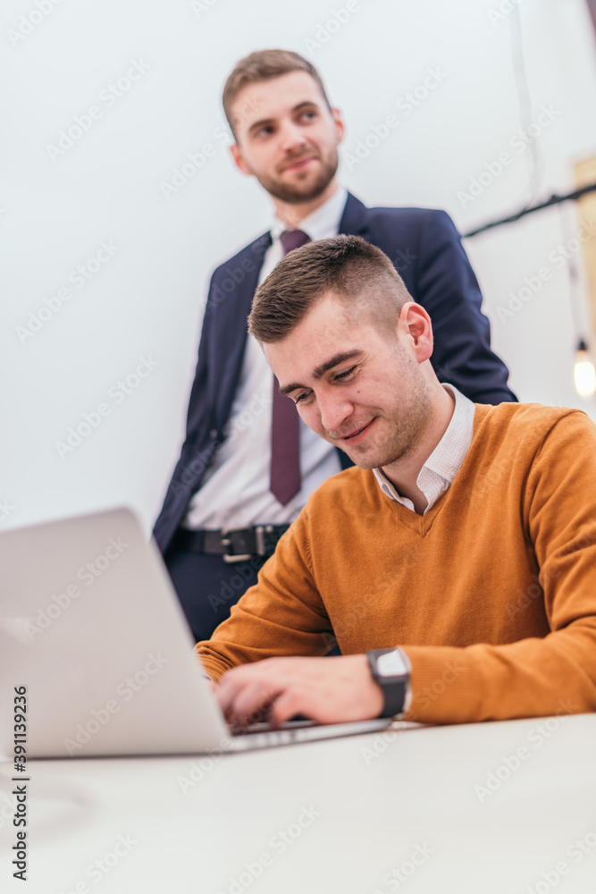 Picture of a businessman working on some final financial details with a suited manager standing next to him Picture of a businessman working on some final financial details with a suited manager standing next to him
