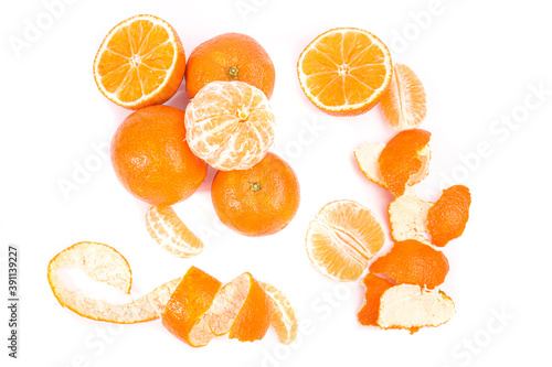 Mandarinas enteras y peladas con cascara y gajos sobre fondo blanco.
