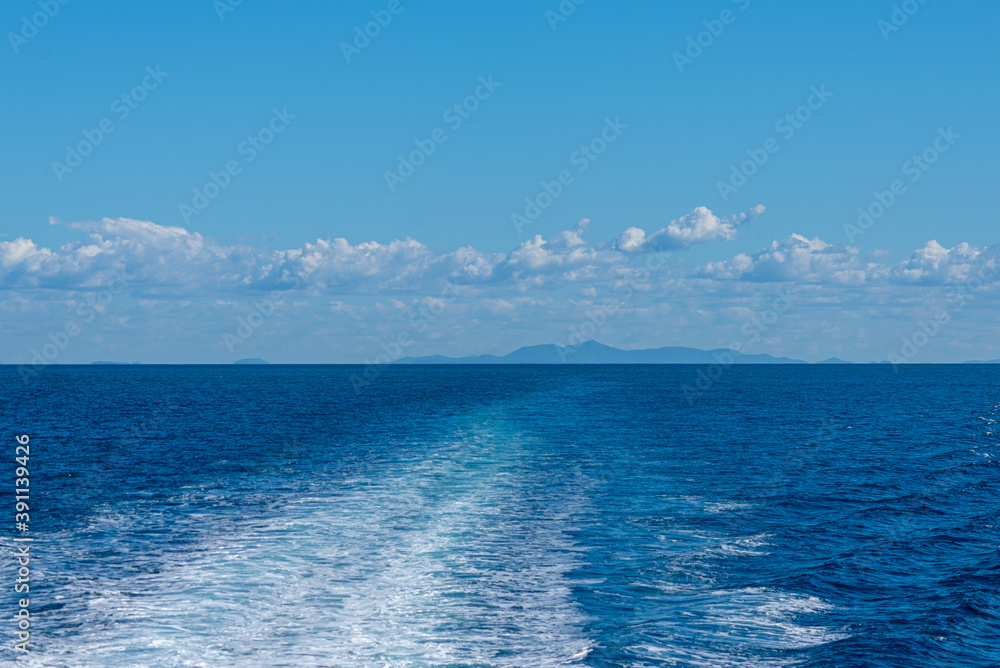 Wake on ocean water with island in background Wake on ocean water with island in background