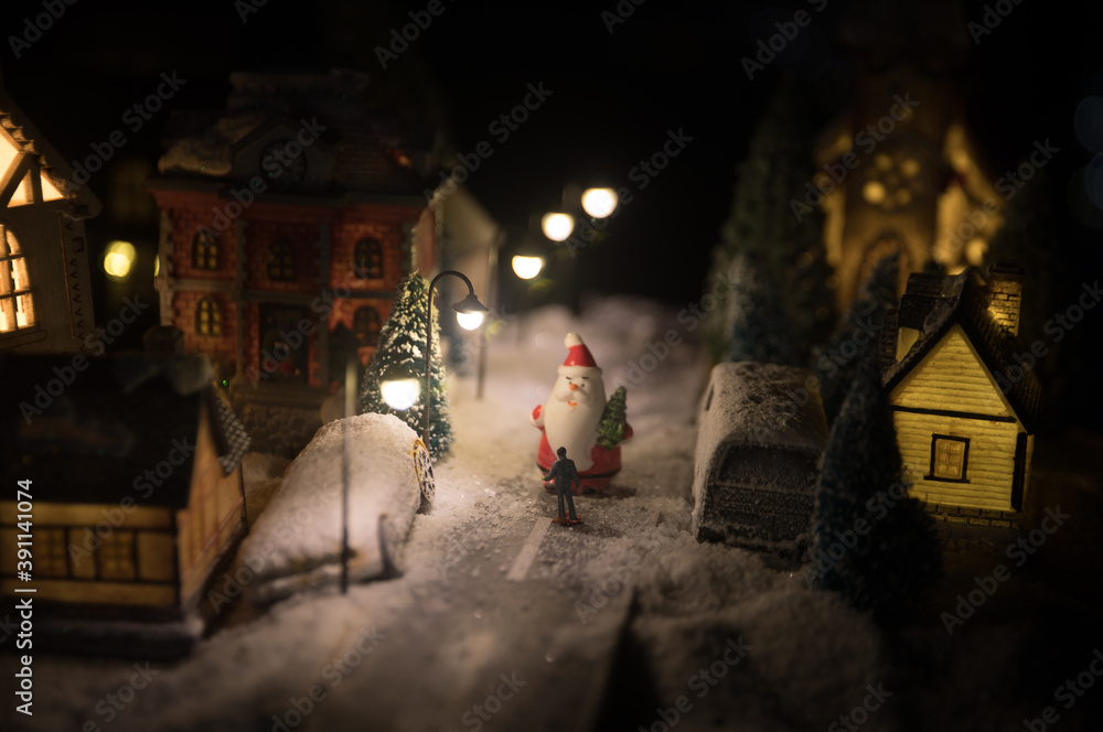 New Year miniature house in the snow at night with fir tree. Holiday concept. Selective focus