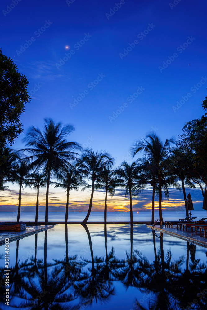 Obraz premium silouette swimming pool with sunbed and coconut tree at seaside resort