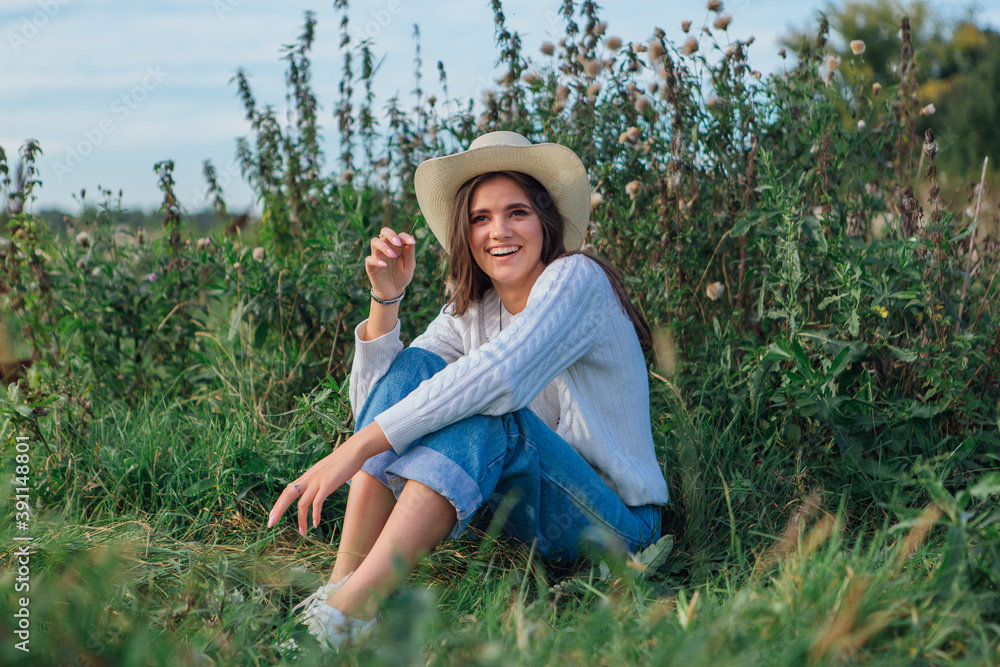 Young beautiful brunette woman sitting on the grass and smiling Young beautiful brunette woman sitting on the grass and smiling