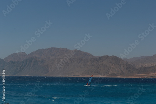 windsurfer on the sea with mountains on background