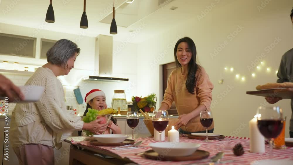 Asian big family preparing foods and drinks to serve on dining table.