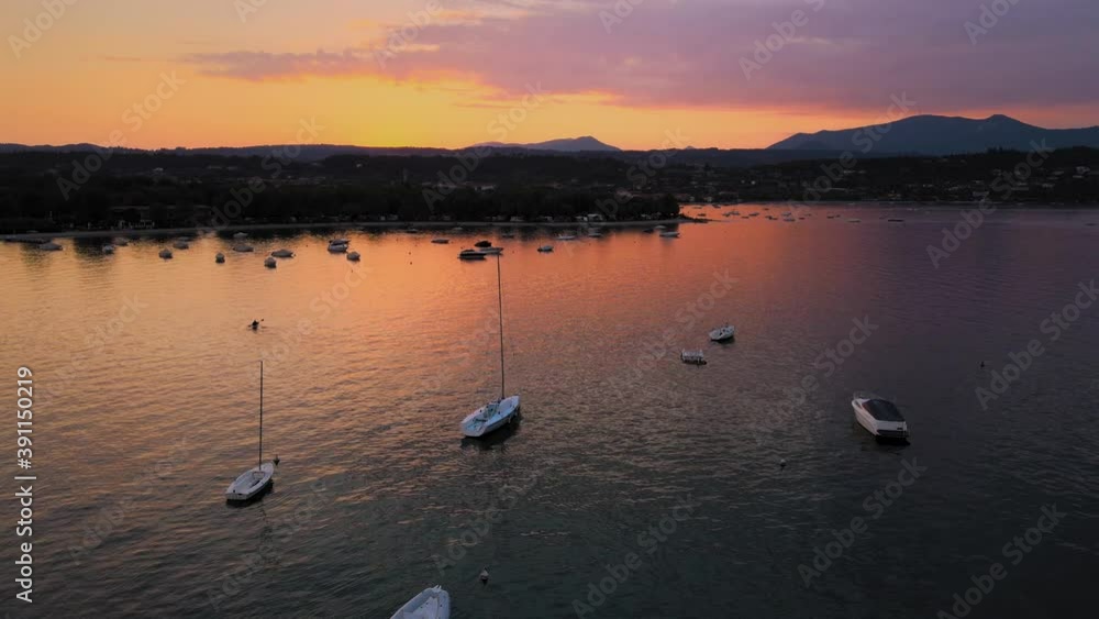 Magical sunset twilight sky above Salo city and lake Garda, Italy. Aerial view of idyllic scenery and boats on water surface, drone shot Magical sunset twilight sky above Salo city and lake Garda, Italy. Aerial view of idyllic scenery and boats on water surface, drone shot
