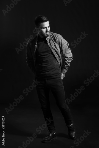 Black and white portrait of fashionable young man on dark background © Pixel-Shot