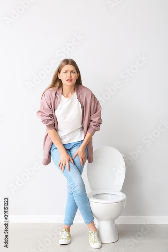Woman with problem of frequent urination in restroom. Diabetes symptoms