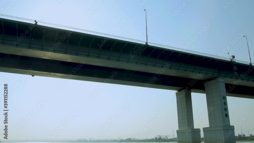 Automobile bridge over a wide river against the background of a blue sky. Sun glare. Automobile bridge over a wide river against the background of a blue sky. Sun glare.