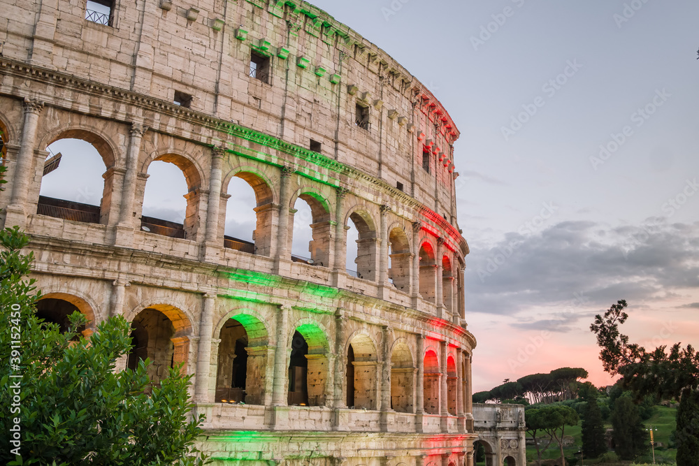 The famous Colosseum in Rome illuminated in Italian flag tricolore at twilight
