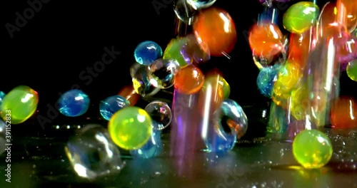 Colorful bouncing glossy wet balls with reflection close-up shot on black background. Wet balls jumping in slow motion and leaving water droplets on the background photo