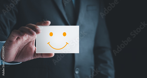 Customer Experience Concept, Businessman holding Card with Smiley Happy Face for his Satisfaction. feedback rating and positive customer review experience