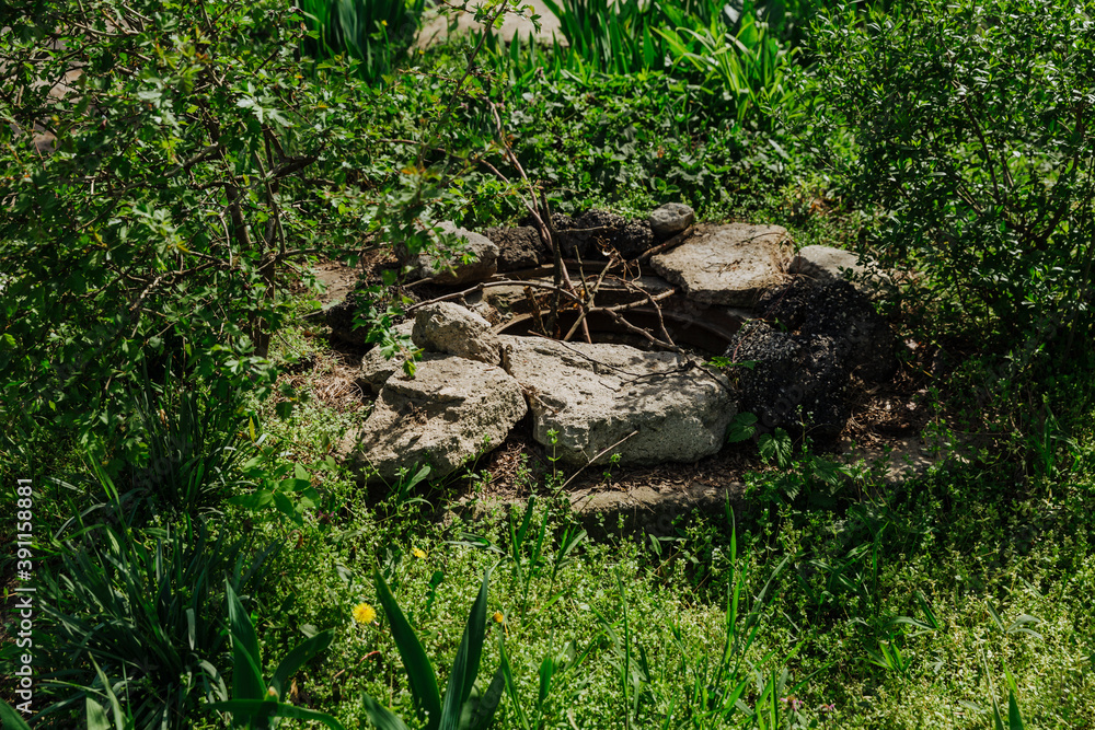 A deep, old, uncovered manhole is dangerous for pedestrians and animals. Instead of a cover, warning tree branches stick out from the hatch A deep, old, uncovered manhole is dangerous for pedestrians and animals. Instead of a cover, warning tree branches stick out from the hatch