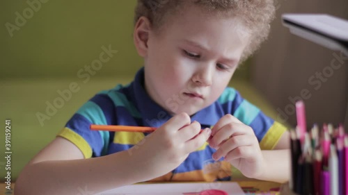 Little boy draws at a table at home. The child is engaged in creativity, studying at home, video