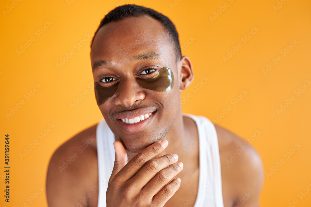 excited afro american man with under eye patches smiling at camera isolated over yellow background, he gets anti aging beauty procedures excited afro american man with under eye patches smiling at camera isolated over yellow background, he gets anti aging beauty procedures