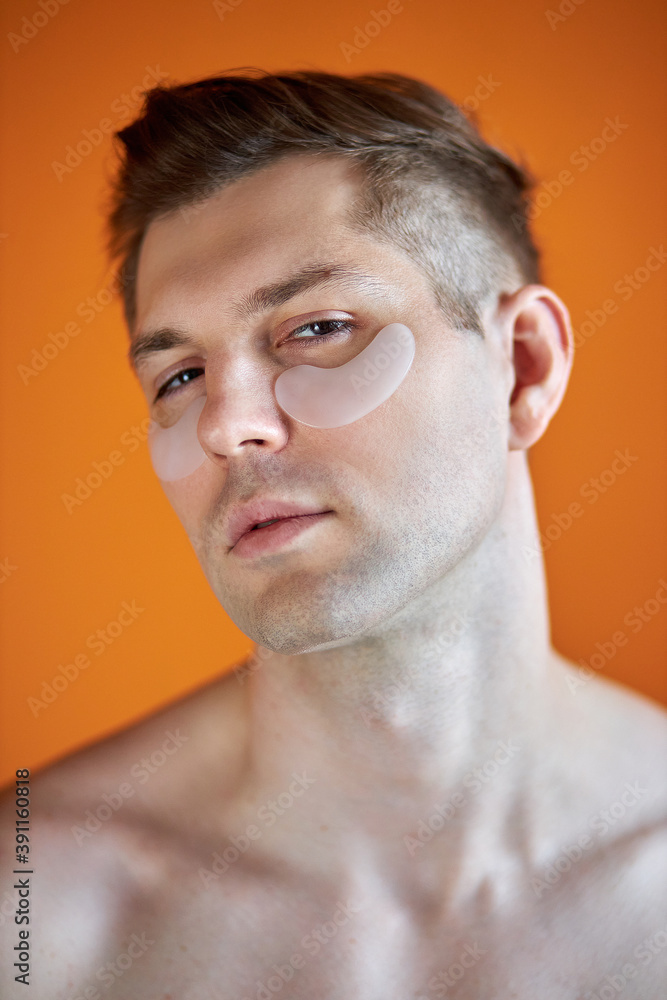 Obraz premium portrait of handsome caucasian guy with transparent patches for dark circles under eyes, enjoy and relax isolated over yellow background
