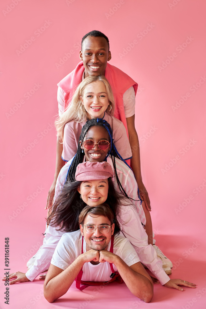 excited interracial group of youth have fun, smile, laugh, isolated onver pink background, they are enjoying time together