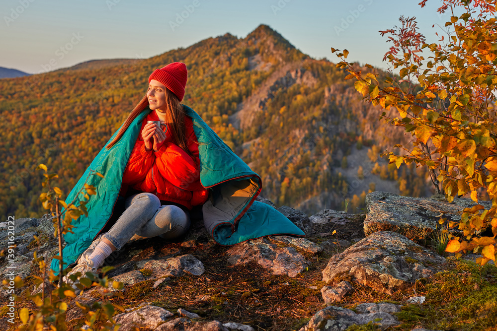 young female traveller sits enjoying hot tea on mountains,have a warm after hiking, wearing warm clothes, in contemplation young female traveller sits enjoying hot tea on mountains,have a warm after hiking, wearing warm clothes, in contemplation
