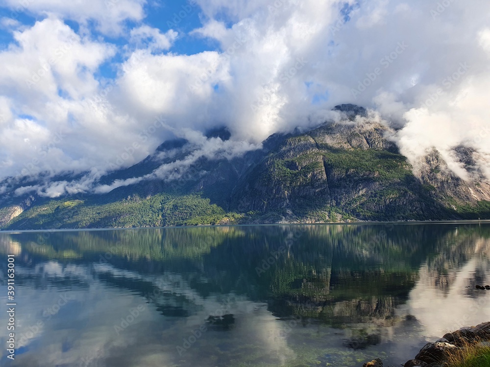 reflection of the sky and mountains in the blue water of the fjord - Eidfjord