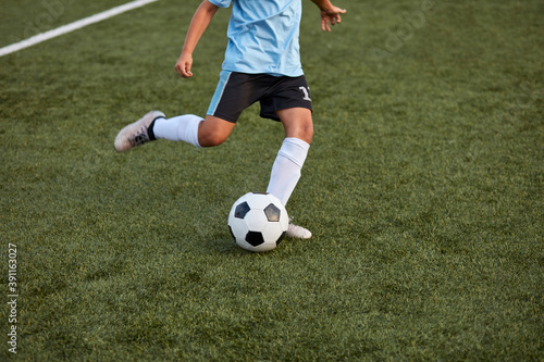 Картината върху платно kid boy kicking soccer ball on sports field, cropped child boy in uniform and sn