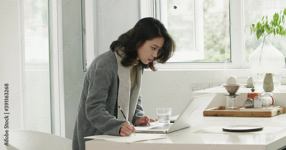 Asian female freelancer working at home office using laptop making design beautiful Chinese designer working in her studio by the window Asian female freelancer working at home office using laptop making design beautiful Chinese designer working in her studio by the window