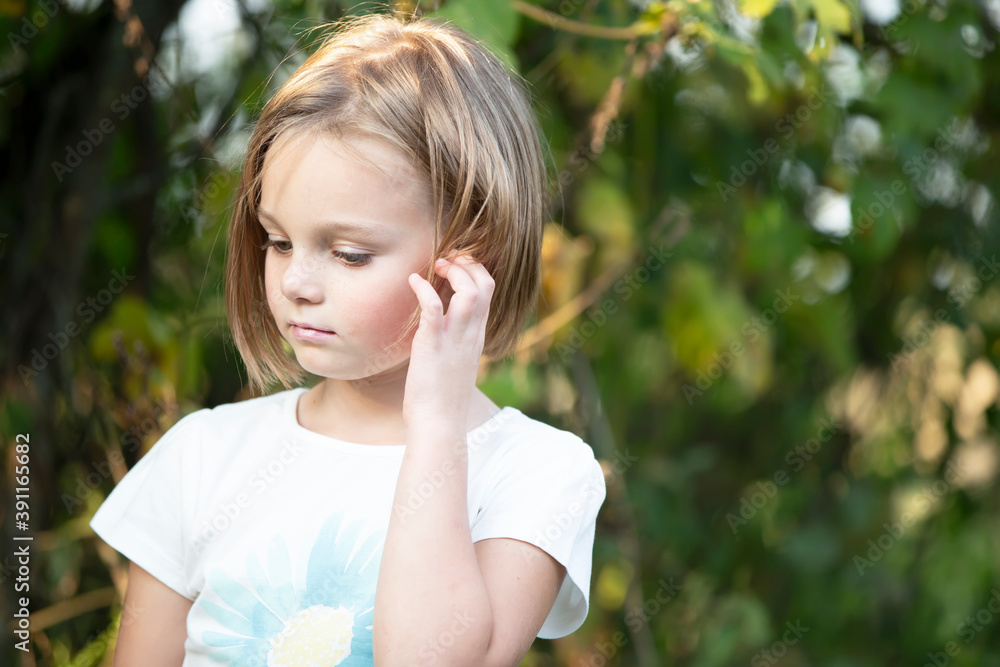 Little sad girl on the background of green bushes. Little sad girl on the background of green bushes.