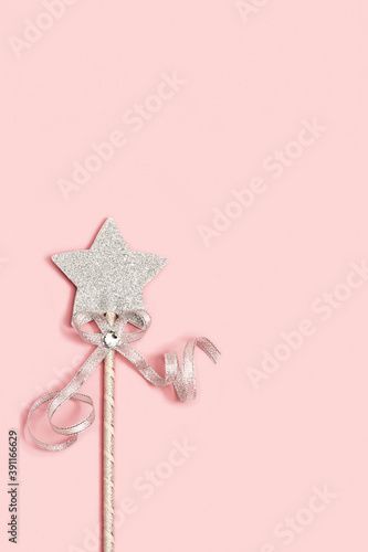 Magic wand, bright silver star with shine on light pink background with copy space. Minimal holiday concept. Copy space. photo