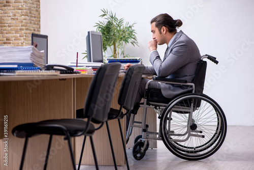 Young male enployee in wheel-chair at workplace