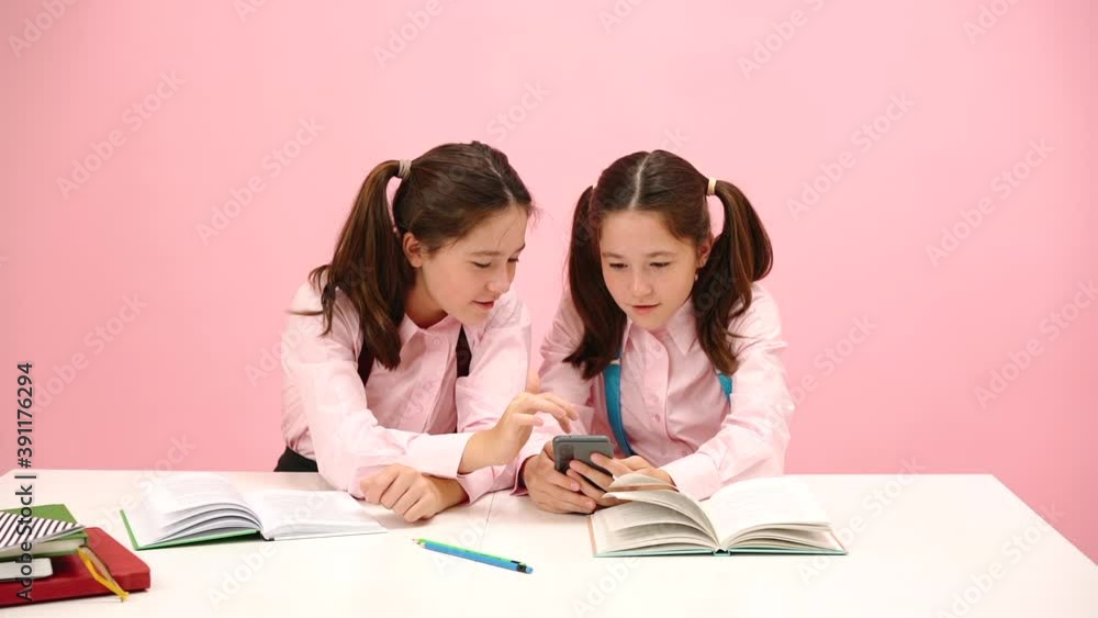 Happy little twin schoolgirls sitting behind school desk. Happy little twin schoolgirls sitting behind school desk.