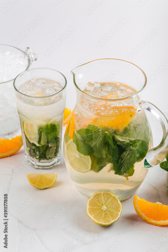Fototapeta premium Orange and lime lemonade in a jug and glass