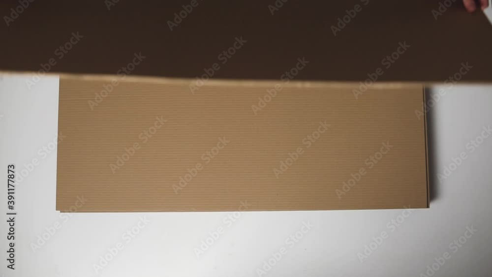 The man takes a sheet of brown cardboard from a pile The man takes a sheet of brown cardboard from a pile