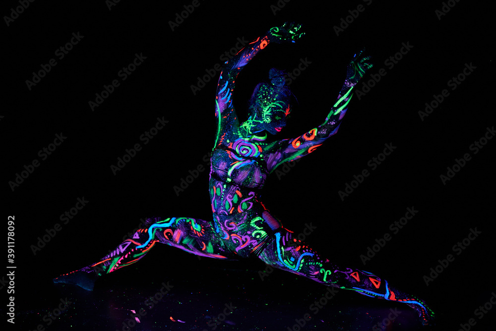 Art woman body art on the body dancing in ultraviolet light. Bright abstract drawings on the woman body neon color. Colored hair and face. Noise, out of focus Art woman body art on the body dancing in ultraviolet light. Bright abstract drawings on the woman body neon color. Colored hair and face. Noise, out of focus