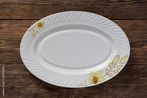 Empty white dish on wooden table, top view