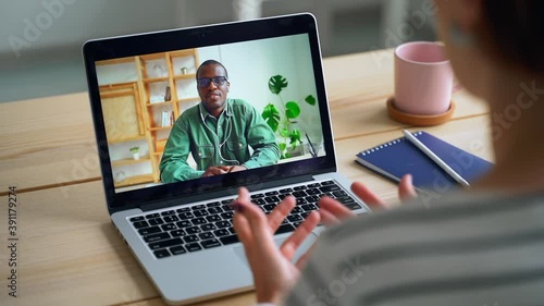 Employee makes conference video call on laptop computer talks with boss Spbas. online work in remote webcam chat on screen. Distance, conference, African concept. Over shoulder distant business.