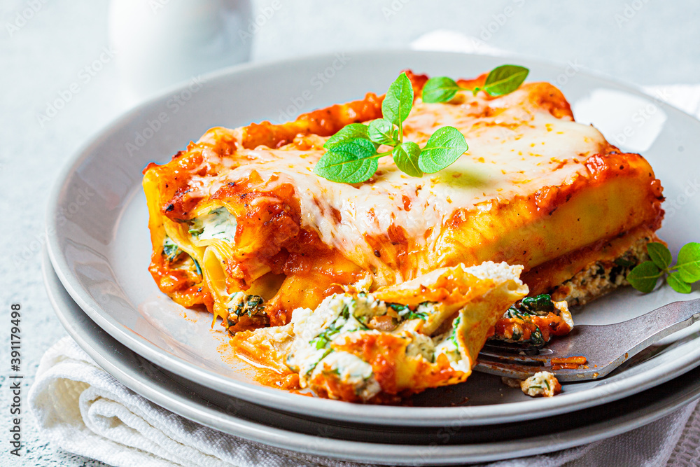 Piece of ricotta and spinach cannelloni on a gray plate. Italian food concept. Piece of ricotta and spinach cannelloni on a gray plate. Italian food concept.