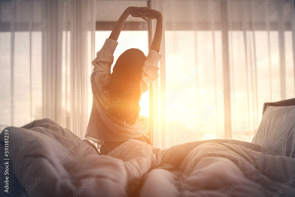 Woman stretching hands in bed after wake up in the morning, Concept of a new day and joyful weekend. - obrazy, fototapety, plakaty 