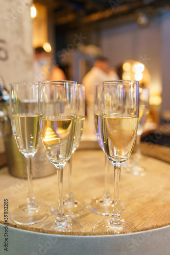 few transparent glasses with champagne on a rack in a bar or restaurant prepared for guests of festive events.